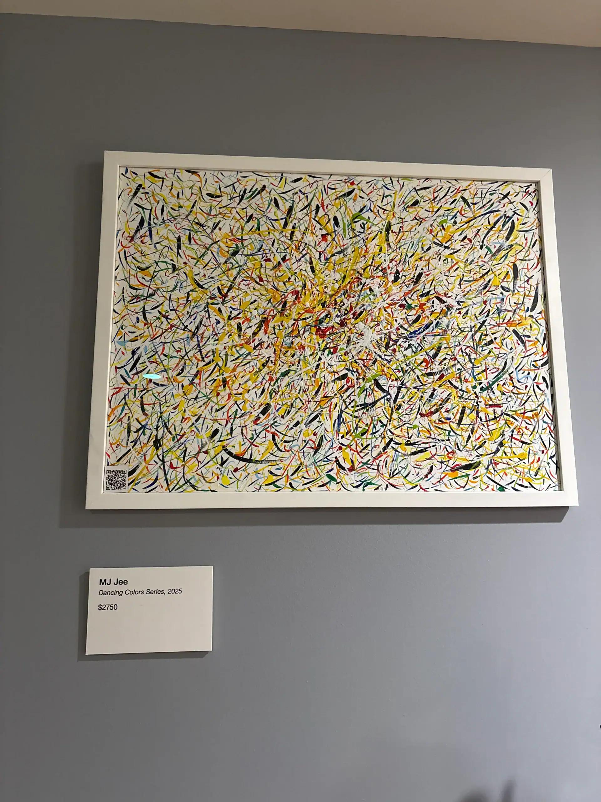 Abstract painting with swirling multicolored lines in a white frame at an NYC Wine Bar & Art Gallery.