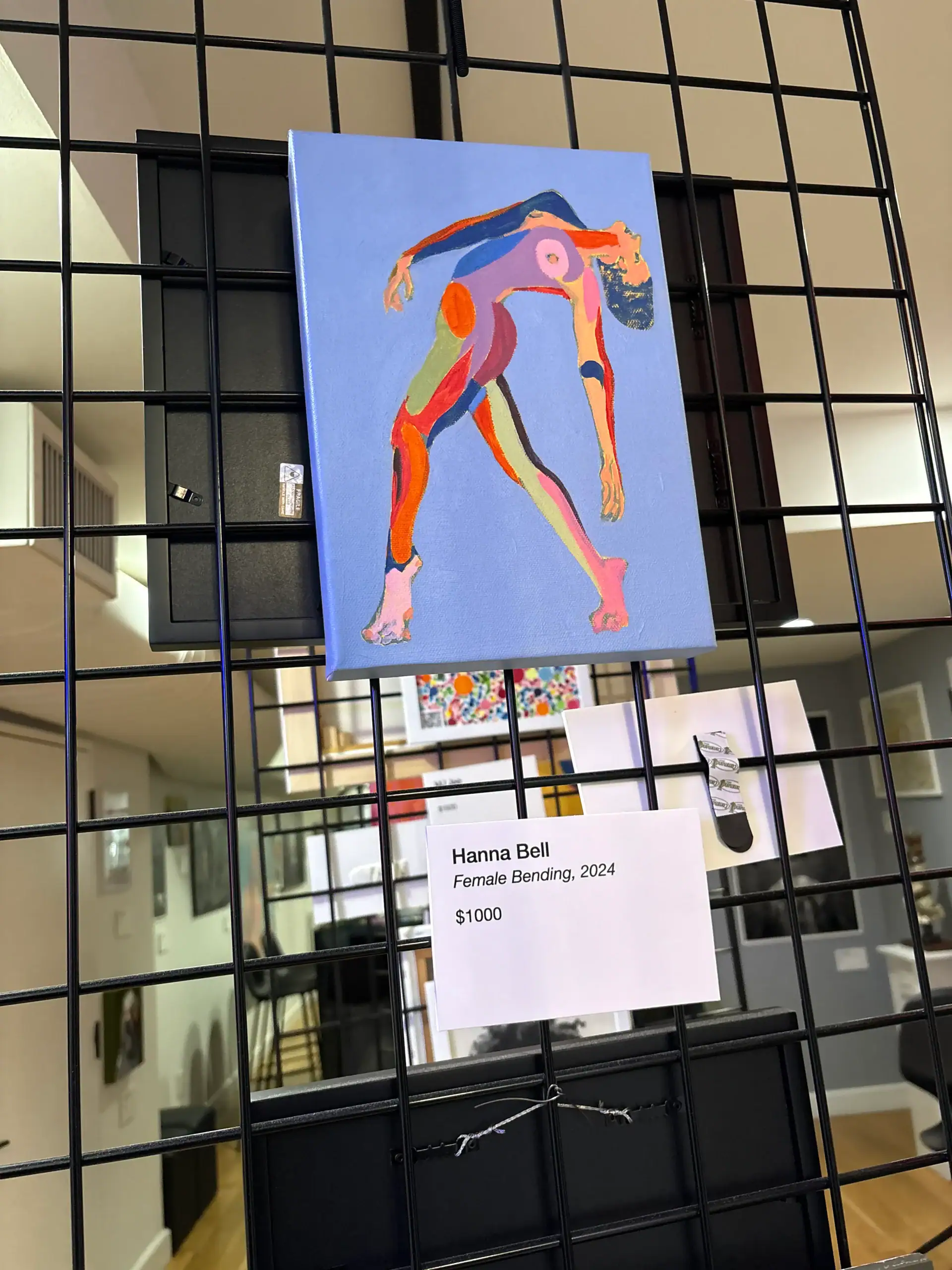 Colorful abstract painting of a bending woman set against blue at a Wine Bar & Art Gallery in NYC.