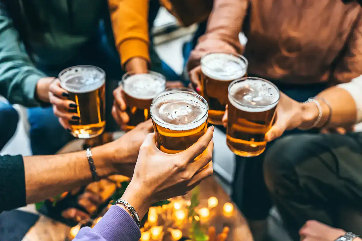 Six people toast beers at a Wine Bar & Art Gallery in NYC, surrounded by warm glowing lights.